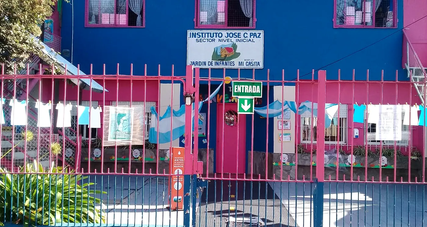 El frente del jardín: la reja rosa, la pared azul y el cartel del Instituto José C. Paz, Jardín de Infantes Mi Casita
