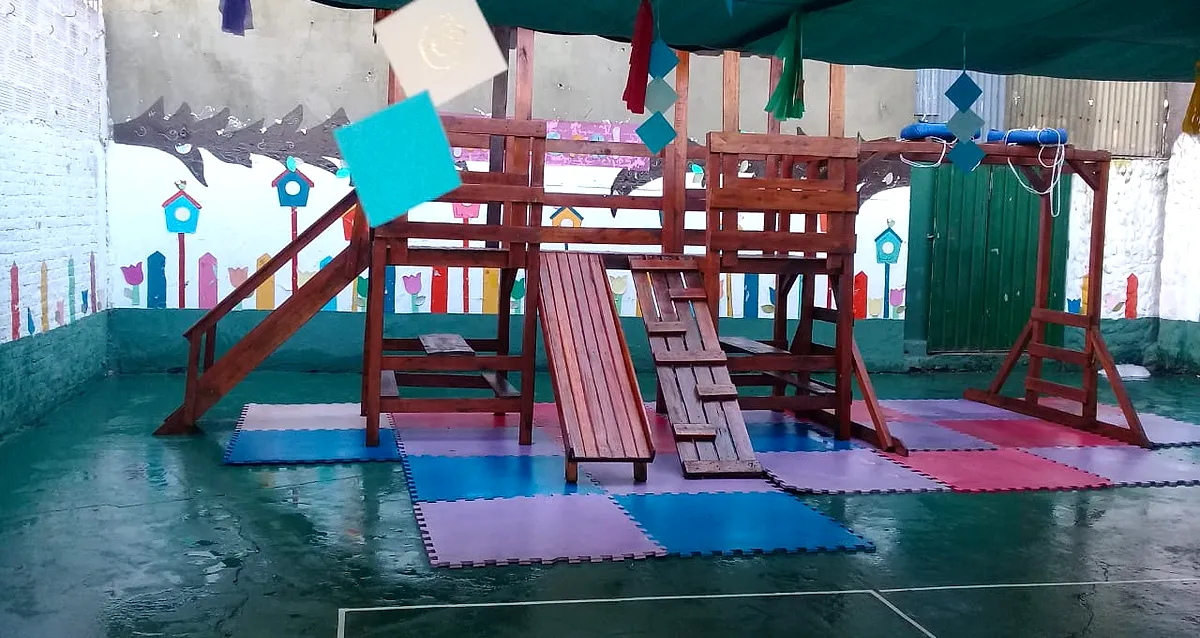 El patio, con el juego de madera y colchonetas de colores